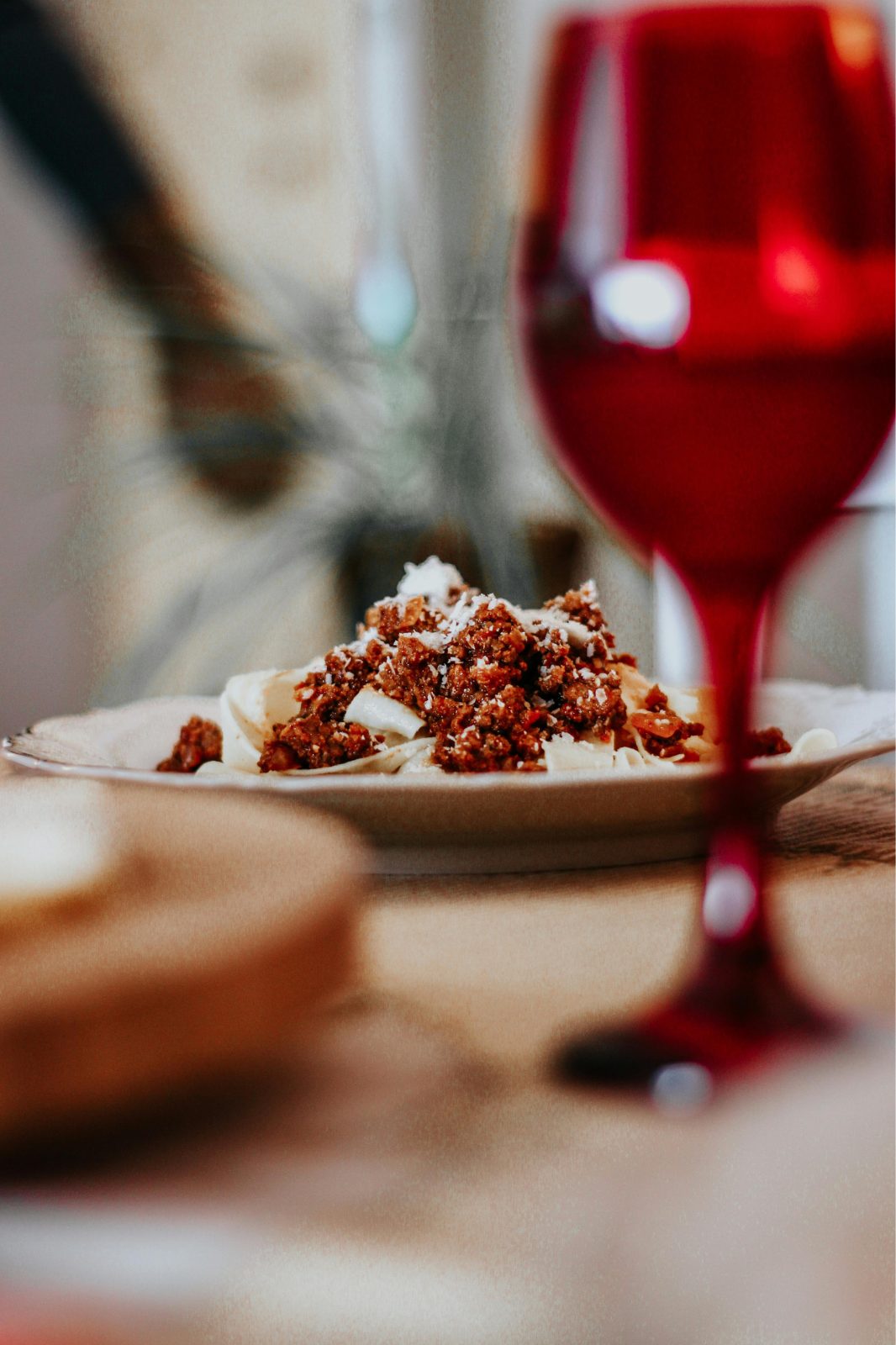 Pasta boloñesa con copa de vino tinto.