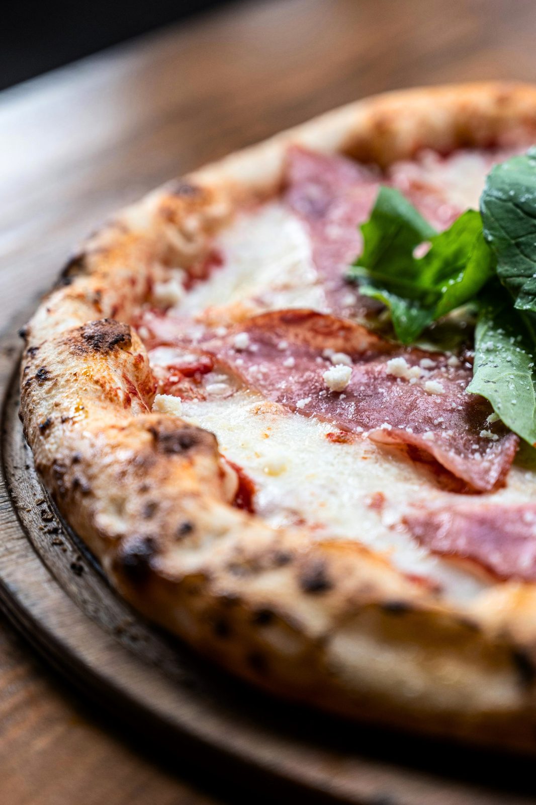 Pizza artesanal al horno con jamón y rúcula.